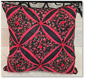 A pillow with red and black design and candles
Description automatically generated